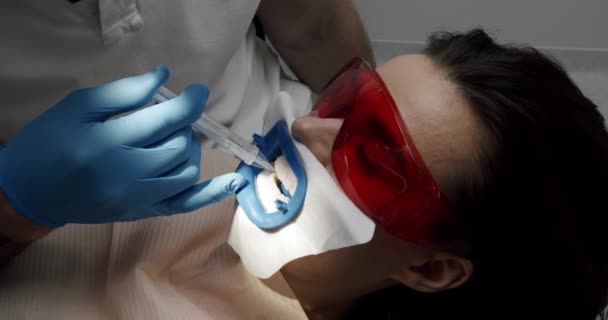 Hammaslääkäri tekee hampaiden puhdistus potilaalle hampaiden moderni klinikka. Suuhygienia ja profylaktinen puhdistus. Naispotilas hygieniahampaiden puhdistustoimenpiteessä hammaslääketieteessä. Moderni hammashoitola. - Materiaali, video