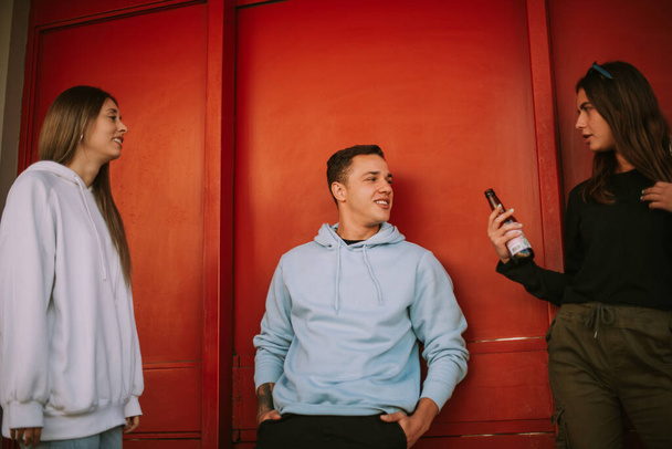 Kolme ystävää puhuu seisoessaan punaisella taustalla - Valokuva, kuva