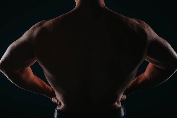 Fizikailag erős férfi mutatja a hátát, sziluett fotó. - Fotó, kép