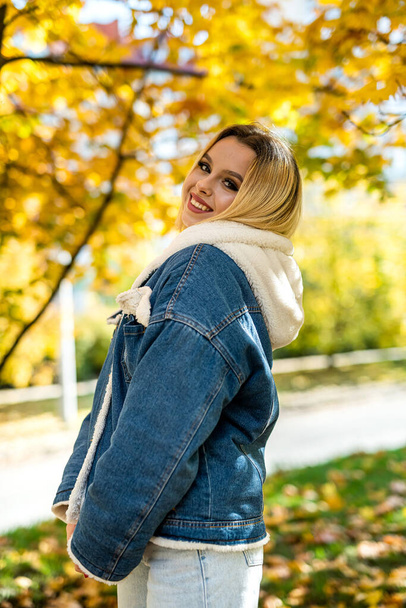 Portrait of pretty young lady walking alone at autumn park outdoor. Enjoy free time - Photo, Image