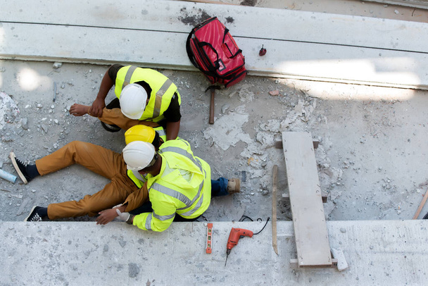 Heat Stroke or Heat exhaustion in body while outdoor work. Accident at work of builder worker at Construction site. Lifesaving, rescue, first aid basic concept. - Photo, Image