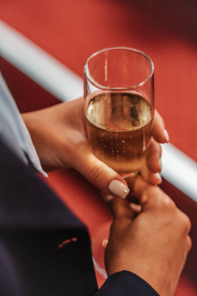 Celebrate milestones and achievements with a lively business team in a vibrant party setting. Woman holding a glass of champagne. Close up photo. - Photo, Image