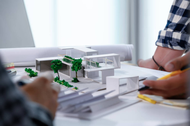 Arkkitehti opiskelija Keskustelu ja kokous noin Home Design paperilla Malli Modern House Miniature Näyte arkkitehti opiskelija, lasiseinä ja energiansäästö kotiin Concept. - Valokuva, kuva