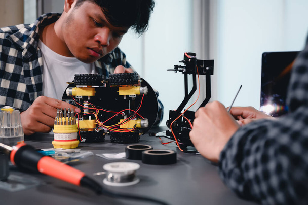 Robot malzemeleri monte eden Asyalı Mühendis Öğrenciler. Mekanik Kontrol 'ü öğrenirken, robotlar bilgisayar, elektrik, mekanik ve algılamayı birleştirir. Mühendisleri ve Geliştirme Konseptini Güçlendirme. - Fotoğraf, Görsel
