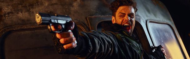 небритый персонаж со стрельбой из пистолета и криками в темноте постапокалиптического метро, баннер - Фото, изображение