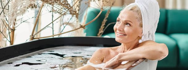 alegre mujer de mediana edad con toalla blanca en la cabeza tomando baño en apartamento moderno, pancarta - Foto, imagen
