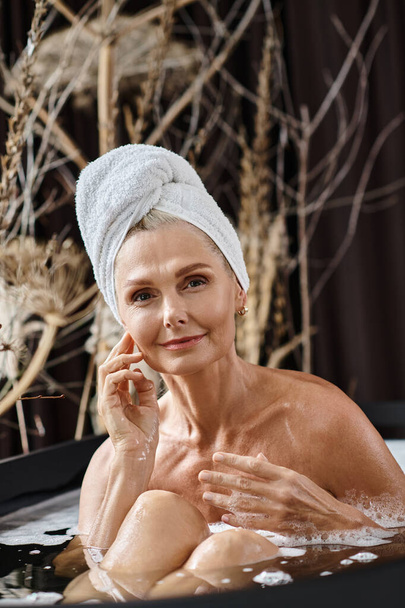 gyönyörű középkorú nő fehér törölközővel a fején fürdés modern apartman, spa nap - Fotó, kép
