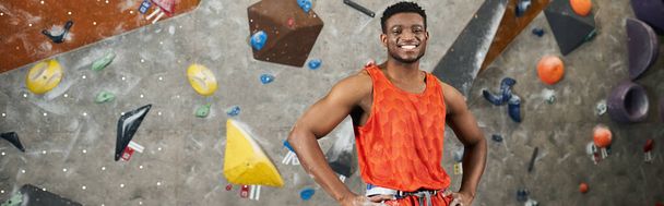 веселий афроамериканський чоловік позує біля скелелазіння стіни і радісно посміхається на камеру, банер - Фото, зображення