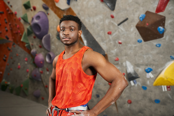 sportovní africký Američan pózuje v oranžové košili s rukama v bok a při pohledu na kameru - Fotografie, Obrázek
