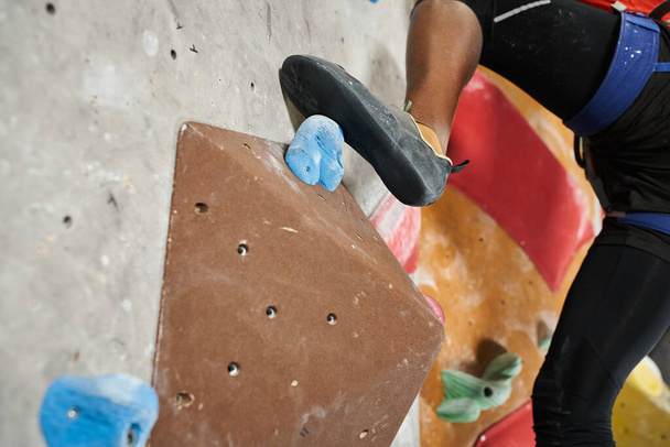 cropped view of foot of sporty african american man on boulder on climbing rock wall, sportsman - Photo, Image