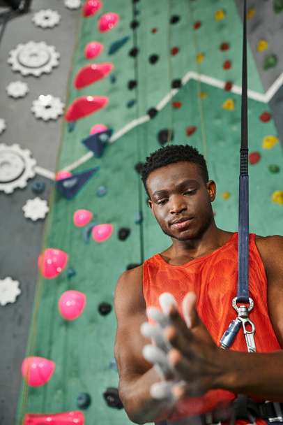 handsome young african american man using gym chalk before climbing up wall, bouldering concept - Photo, Image