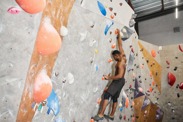 atlético sem camisa afro-americano homem em calças pretas escalando parede de rocha sem corda de segurança - Foto, Imagem