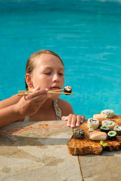 chica en bikini con un plato de sushi junto a la piscina - Foto, Imagen