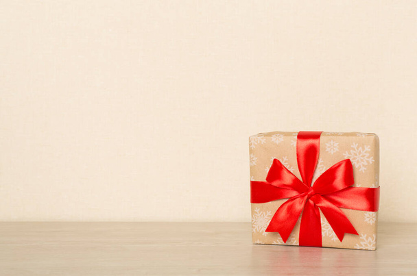 Κουτί δώρου με κόκκινη κορδέλα φιόγκο σε φωτεινό τραπέζι. - Φωτογραφία, εικόνα