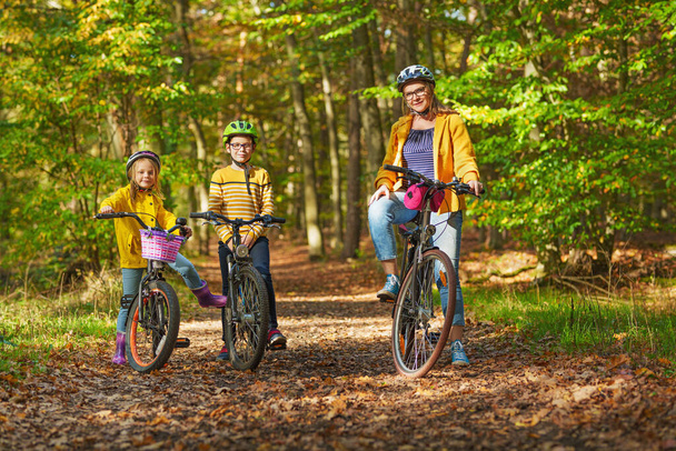 Jonge familie met zoon en dochtertje op de fiets, midden in de herfstnatuur. - Foto, afbeelding