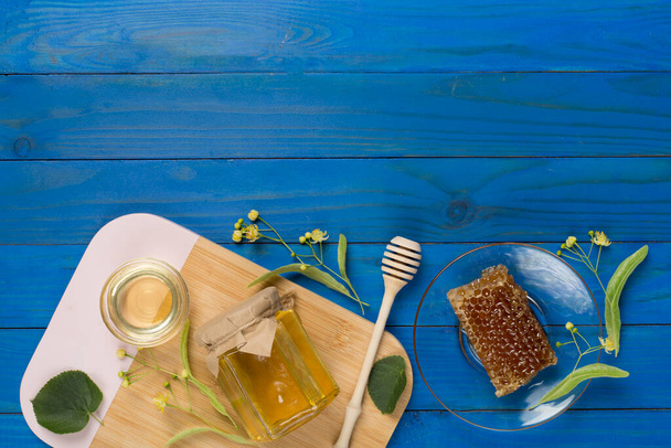 Linden μέλι με φύλλα και λουλούδια στο ξύλινο backgroung, top view - Φωτογραφία, εικόνα
