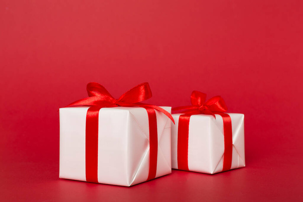 Κουτιά δώρου με κόκκινη κορδέλα φιόγκο στο φόντο χρώμα. - Φωτογραφία, εικόνα