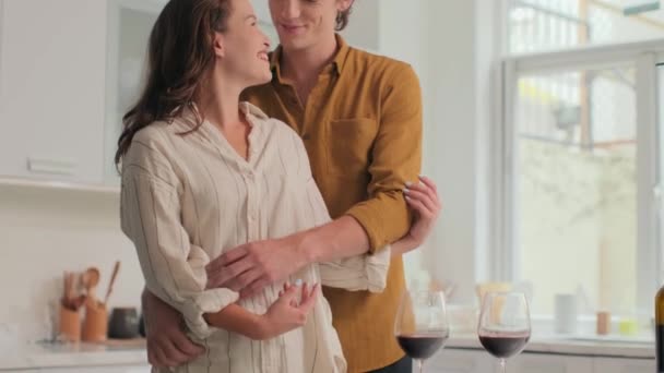 A boldog fiatal feleség és férj portréja, amint szeretettel ölelgetik egymást, miközben romantikus vacsorát vacsoráznak otthon a feleségükkel, a kamerába néznek. - Felvétel, videó