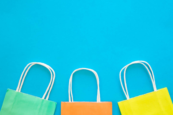 Bolsas de papel de diferentes colores sobre un fondo azul, vista superior, concepto de compras, espacio de copia. - Foto, imagen