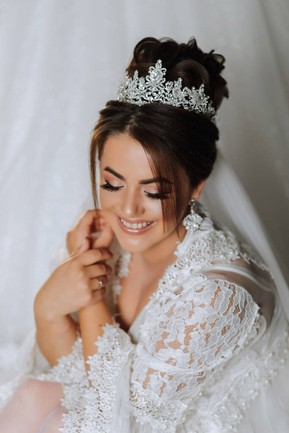 Gorgeous bride portrait in her robe wearing tiara. Beautiful bridal makeup and hairstyle and hair accessories. Bride to be smiling portrait - Fotografie, Obrázek