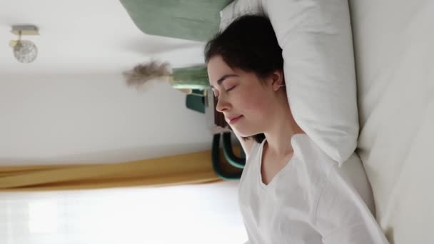 Zijaanzicht van de jonge blanke gelukkige vrouw ontwaakt uit zacht kussen met orthopedische matras. Gezond slapen en goedemorgen. Linkerschot vrachtwagen - Video