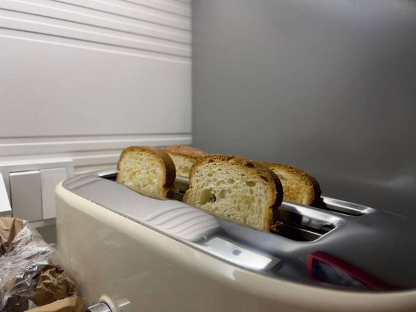 側面から捉えられたトースターにきちんと配置された4枚のパンのスライス. - 写真・画像