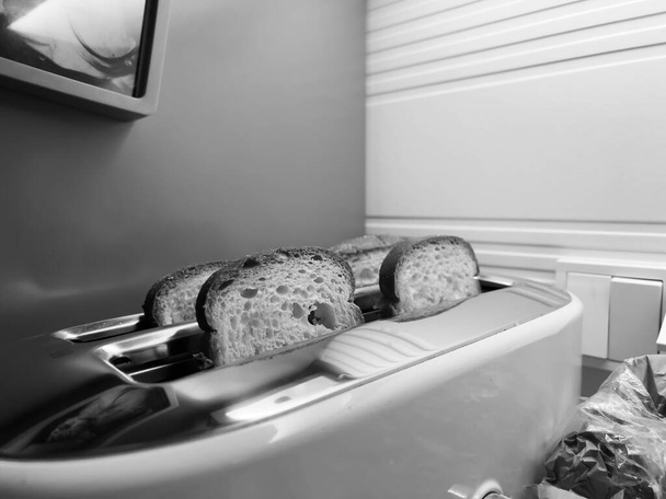 A classic black and white photograph of four slices of bread snugly fitted into a toaster, showcasing its timeless design. - Photo, Image