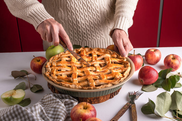 Vrouw snijden van een gebakken appel met een khife, Thanksgiving traditionele dessert klaar om te eten met rode en groene appels, Thanksgiving taart voorbereiding, herfst bakkerij. Knapperig weer snoep. Recept - Foto, afbeelding