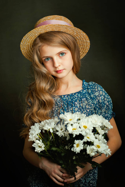 Κοντινό πλάνο Πορτρέτο ενός όμορφου ξανθού κοριτσιού με μπλε μάτια σε vintage φόρεμα. Όμορφο παιδί με λαμπερά σγουρά μαλλιά ποζάρουν στο στούντιο σε σκούρο φόντο. - Φωτογραφία, εικόνα