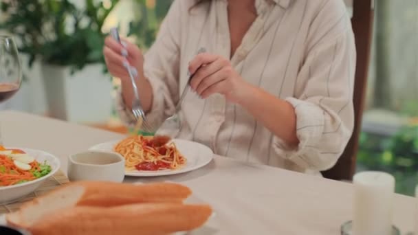 Середній знімок молодої жінки, насолоджуючись макаронами з томатним соусом, вечеряючи вдома - Кадри, відео