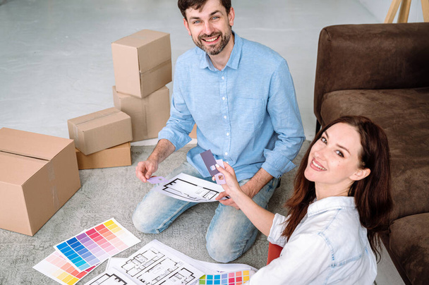 Junges Ehepaar wählt Farben für neues Zuhause, überprüft Papierbroschüre mit Mustern, verschiedene Muster, plant Renovierung nach dem Einzug in neue Wohnung - Foto, Bild