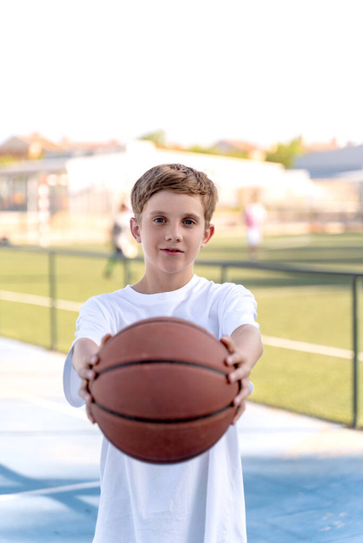 バスケットボールを屋外でポーズする若い男の子の肖像. スポーツコンセプト. - 写真・画像