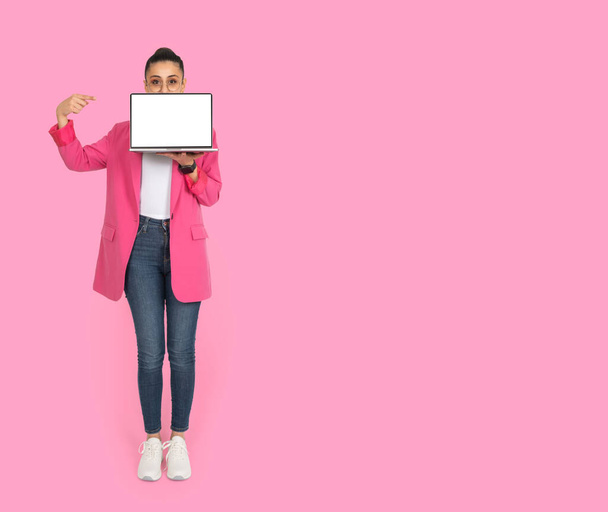Laptop mock up, full body profile portrait of business woman holding laptop mock up. Cover her face with computer pc. Pointing empty white blank screen. Pink background, copy space. Website advert. - Photo, Image