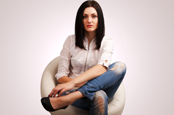 Mulher de jeans sentada na cadeira
 - Foto, Imagem