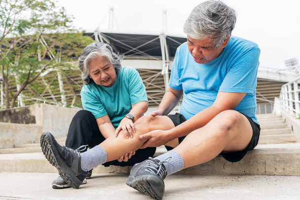 Asiatisches älteres Ehepaar, Frau, die die Beinmuskeln ihres Mannes mit Verletzungen zusammendrückt, krämpft beim Sport. Menschen im Rentenalter Gesundheitsversorgung und Muskelkrämpfe Konzept. - Foto, Bild