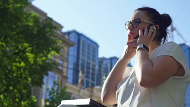 Embracing Business Dynamism: Biegła bizneswoman Angażowana w rozmowy i rozmowy telefoniczne podczas spaceru wśród Urban Business District. Wysokiej jakości materiał 4k - Materiał filmowy, wideo