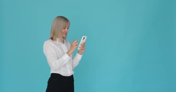Vrouw is afgebeeld ontvangen geweldig nieuws op haar telefoon, en ze roept enthousiast Wow tegen een blauwe achtergrond. Haar uiting van verbazing en verrukking toont haar positieve reactie op het nieuws. - Video