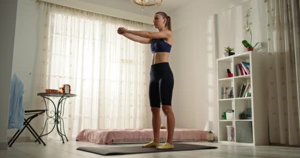 Девушка выполняет упражнения, упорно тренируется дома в гостиной. Тяжелая работа на стройном теле, диете, активном спортивном образе жизни. Высококачественные 4k кадры - Кадры, видео