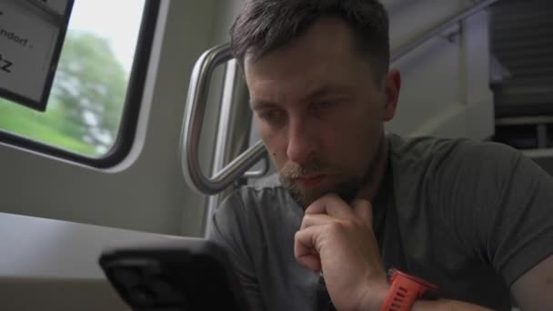 Młody człowiek podróżuje dwupokładowym pociągiem i siedzi na ulotce za pomocą smartfona. Brak wolnych miejsc podczas podróży koleją. Mężczyzna dojazdy w pociągu dwupokładowym siedzi na ulotkach i surfing internet.  - Materiał filmowy, wideo