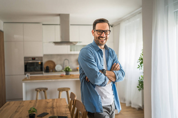 One man adult portrait of caucasian male with beard and eyeglasses stand at home happy smile copy space - Photo, Image