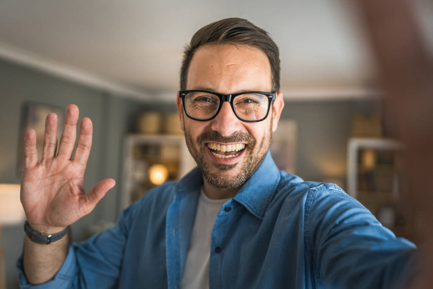 Un homme adulte portrait de caucasien mâle avec barbe et lunettes se tenir à la maison heureux sourire copie espace autoportrait selfie - Photo, image
