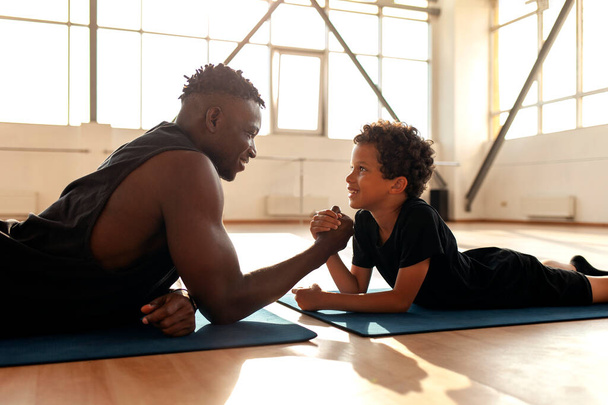 afro-américain garçon 9 ans rivalise avec papa dans le bras de fer, père entraîne son fils et teste sa force, le concept de l'éducation et un mode de vie sain - Photo, image