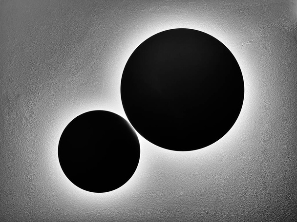 Arkkitehtoninen abstrakti kahden valaisimet seinällä muistuttaa kuun kiertoradalla maan. - Valokuva, kuva