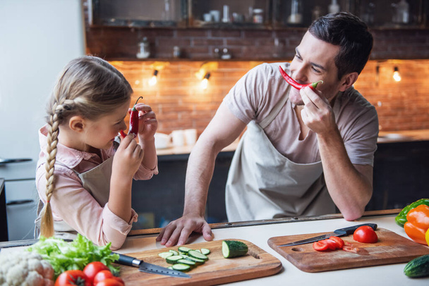 Söpö pieni tyttö ja hänen komea isänsä pitävät hauskaa ruoanlaitossa kotona - Valokuva, kuva