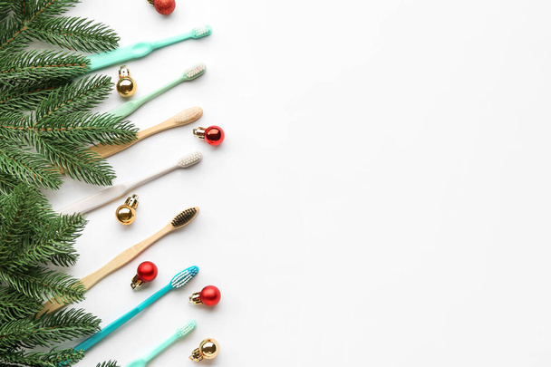 Spazzolini da denti con palline di Natale e rami di abete su sfondo bianco - Foto, immagini