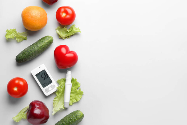 Γλυκόμετρο, lancet, κόκκινη καρδιά, φρέσκα λαχανικά και φρούτα σε λευκό φόντο. Έννοια διαβήτη - Φωτογραφία, εικόνα
