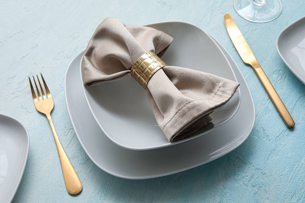 Altın çatal bıçak ve açık mavi masa peçetesiyle şık bir masa. - Fotoğraf, Görsel