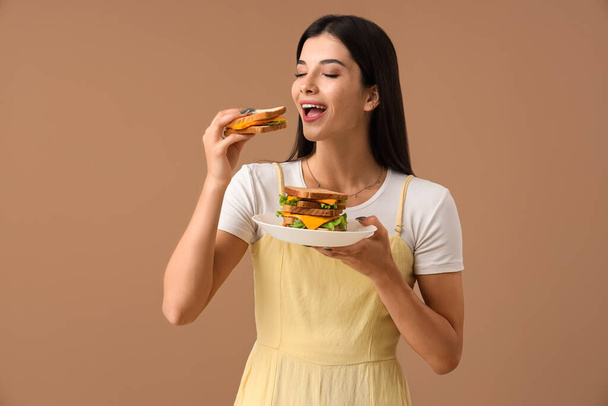Jonge vrouw met lekkere sandwiches op kleur achtergrond - Foto, afbeelding