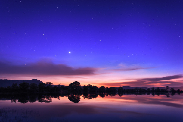 Όμορφο νυχτερινό ουρανό με τα αστέρια, τα σύννεφα και αντανακλάσεις στο το wa - Φωτογραφία, εικόνα