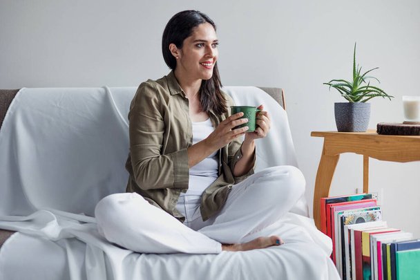 латинская взрослая женщина руки держа чашку кофе с пеной дома утром, латиноамериканка любительница кофе - Фото, изображение